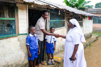 Schwester Irene bringt nach dem Unterricht die Schüler John Adawan und John Adu zu ihrem Vater John Baidoo nach Hause. pde-Foto: Fritz Stark/missio