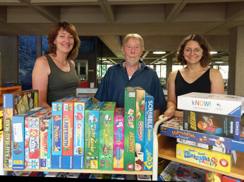 Ein Teil der neuen Spiele, Doris Hammerbacher und Franziska Meyer aus der Stadtbibliothek und Jürgen Höhn vom Spieleclub Neumarkt. Foto: Hauke Höpcke